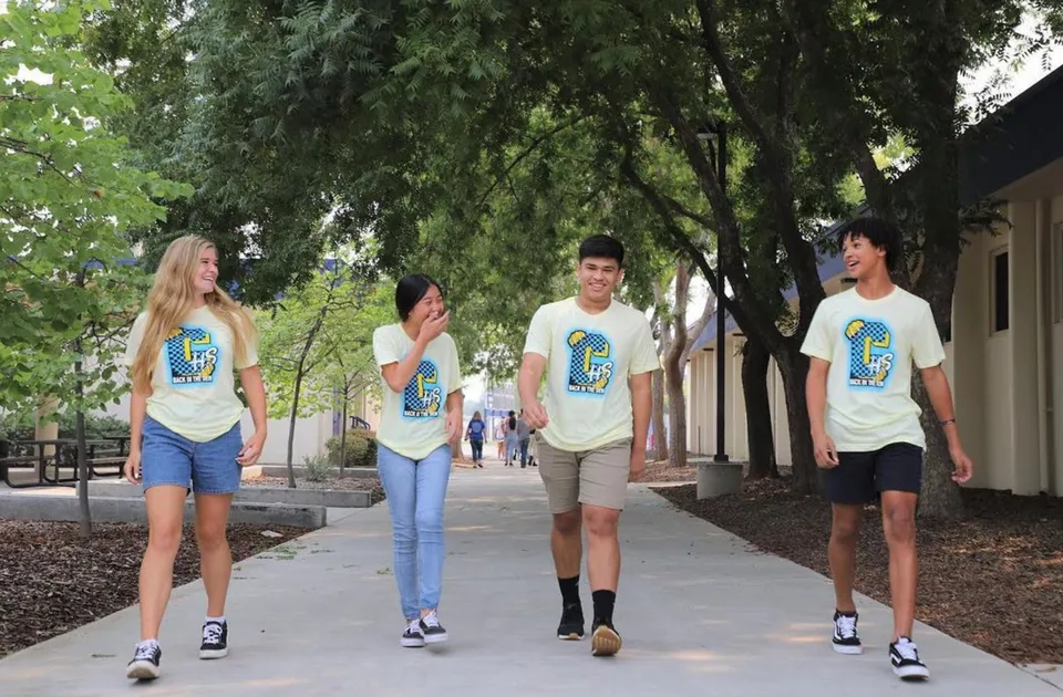 Un gruppo di studenti della Clovis High School cammina insieme lungo un viale alberato.