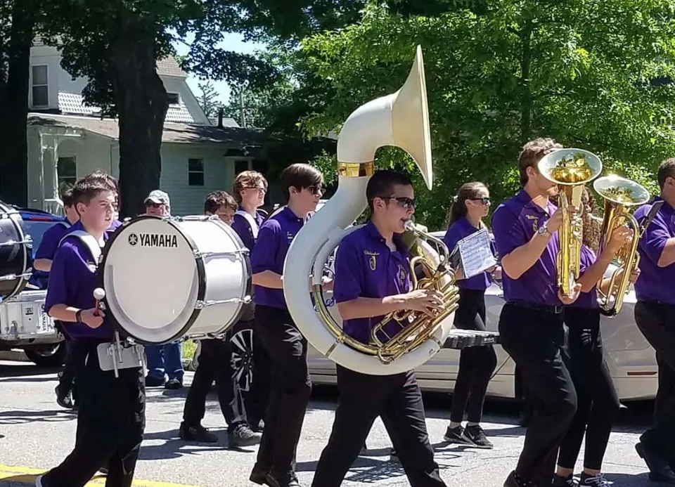 Un gruppo musicale in uniformi viola suona per strada davanti agli edifici del campus della Warwick Valley High School.