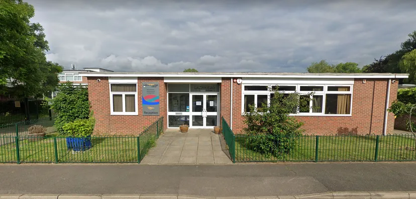 L'edificio in mattoni a un piano della Larkmead School con grandi finestre e cortile recintato sotto un cielo nuvoloso.