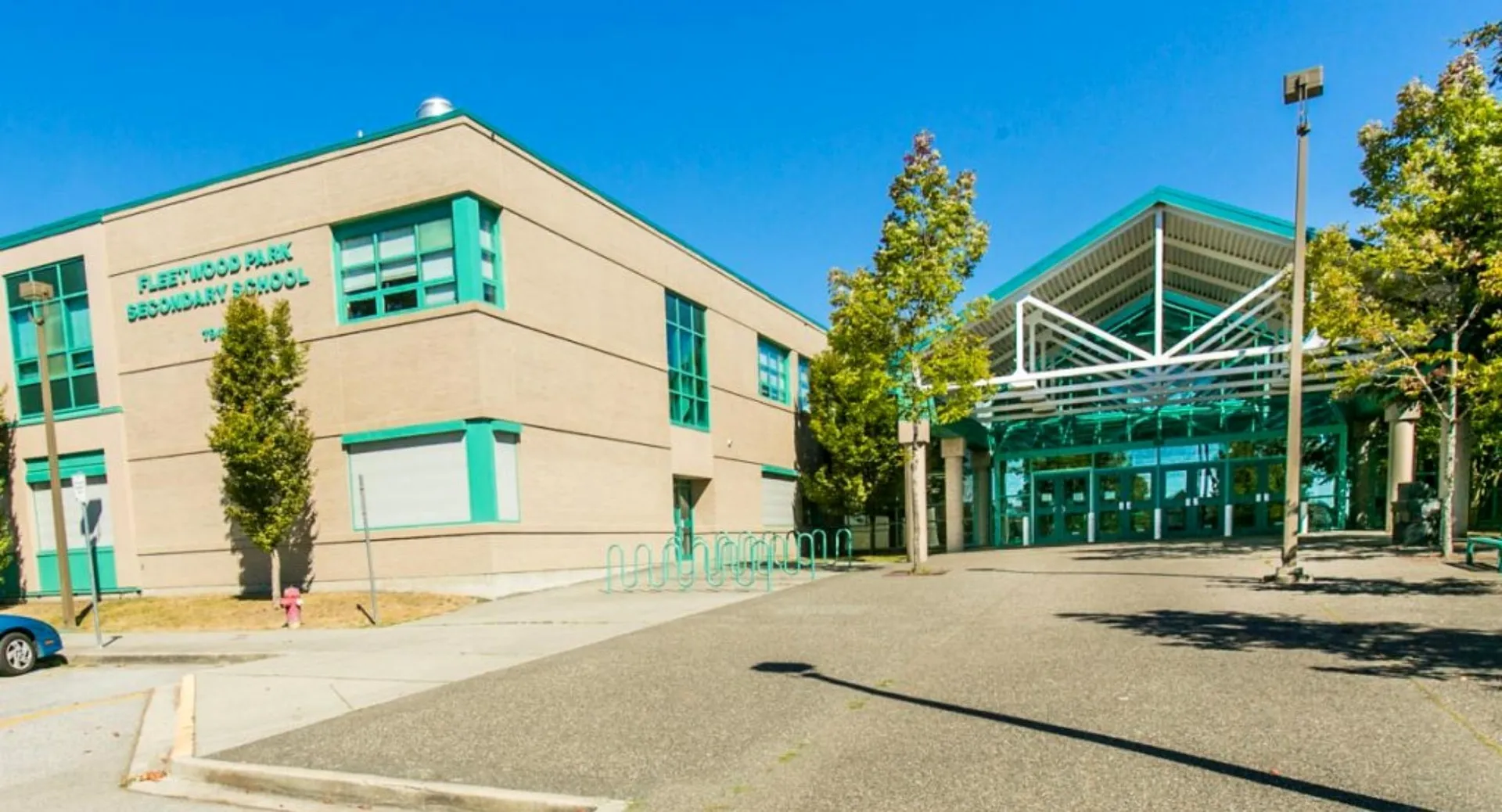 L'edificio moderno a più piani della Fleetwood Park Secondary School è circondato da alberi e da un viale pavimentato.