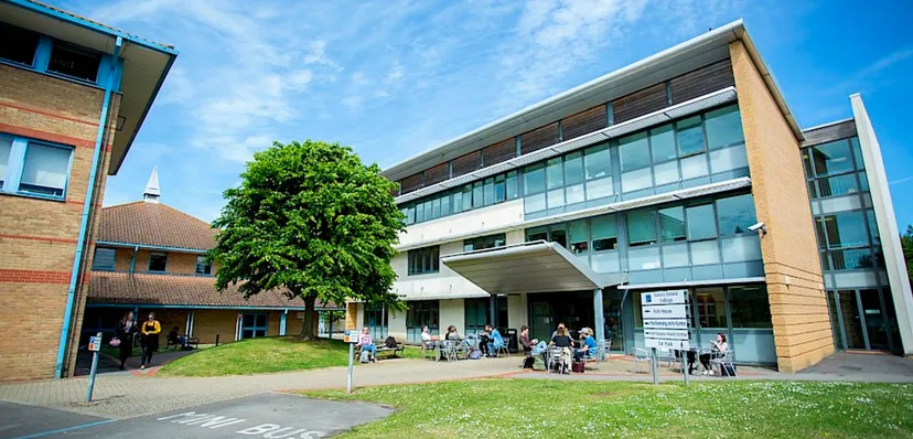 L'edificio moderno dell'East Sussex College Lewes con un cortile dove alcuni studenti siedono a tavoli all'aperto.