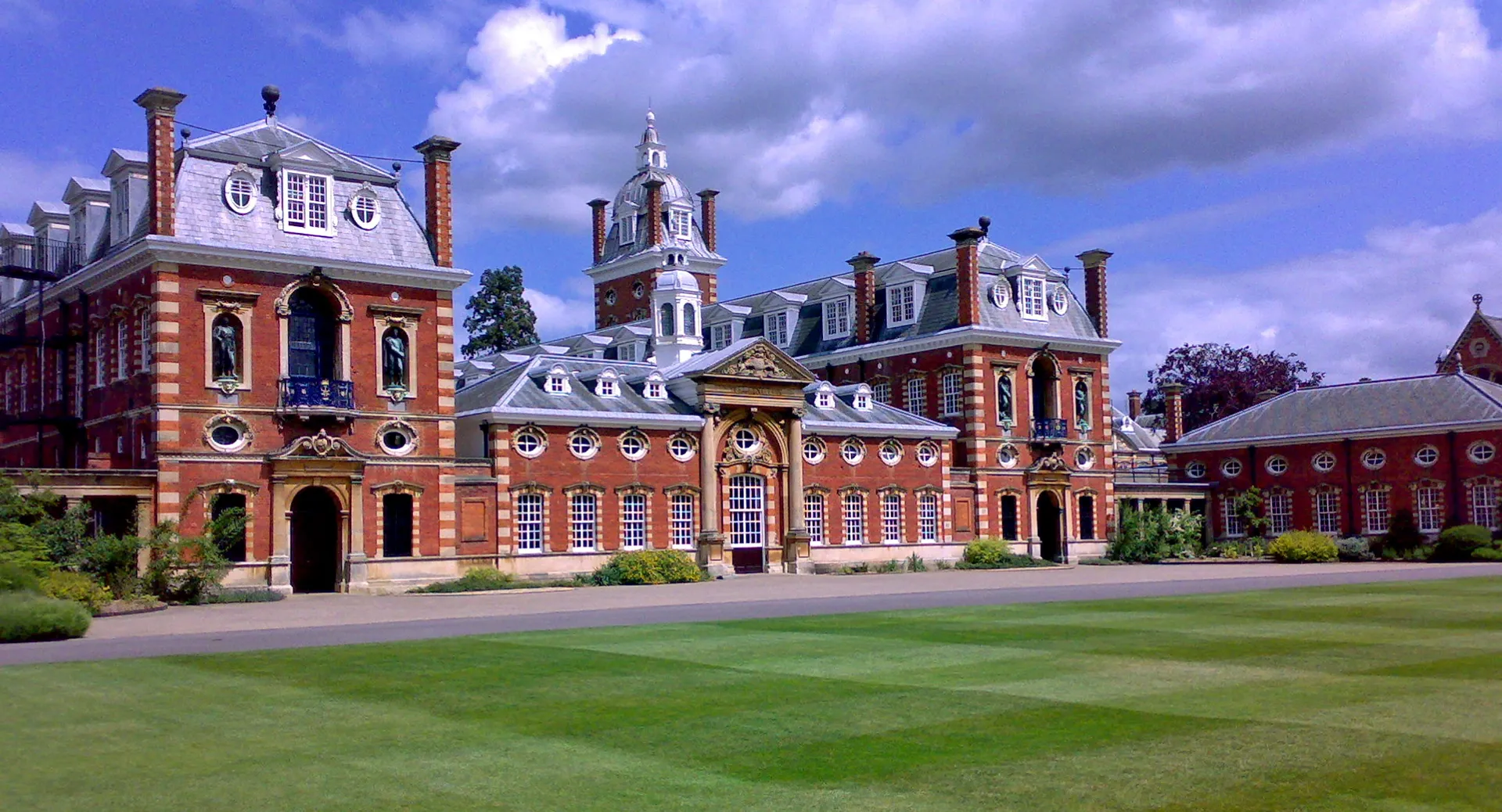L'edificio storico in mattoni rossi del Wellington College con un prato curato in primo piano.