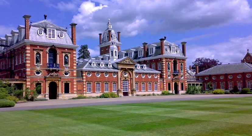 Il Wellington College mostra un edificio storico in mattoni con una torre centrale e un prato ben curato sotto un cielo nuvoloso.