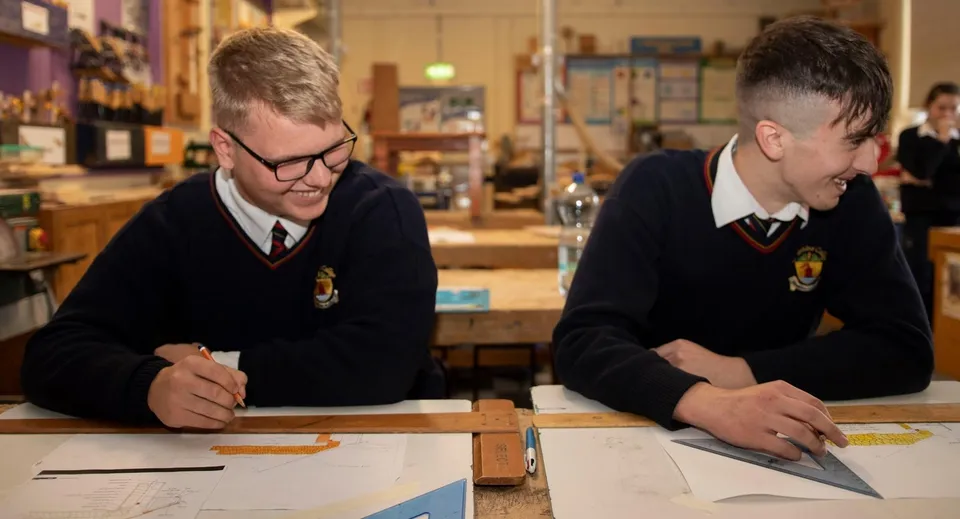 Due studenti della Cabinteely Community School siedono insieme a un tavolo concentrandosi sul loro lavoro.