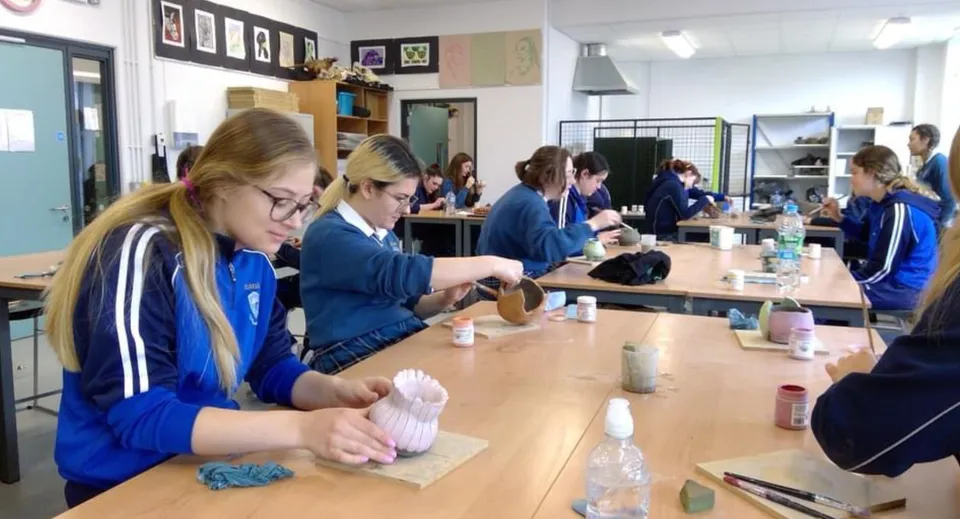 Gli studenti della Eureka Secondary School indossano divise blu e sistemano del materiale in un'aula.