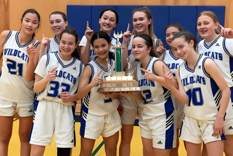 Un gruppo di giovani giocatrici di basket della École Secondaire R.A. McMath Secondary School festeggia la propria vittoria con una coppa sul campo da basket.