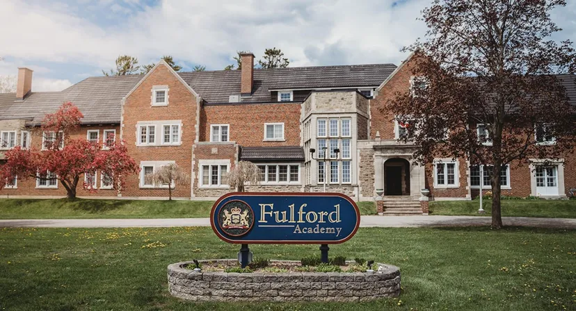 L'edificio in mattoni e pietra della Fulford Academy si trova su un terreno verde con alberi ed è circondato da edifici simili.