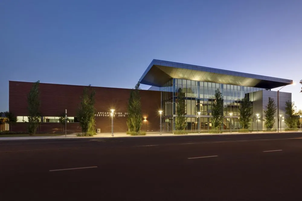 El edificio del Performing Arts Center de la Arcadia High School al atardecer con fachada de cristal iluminada.