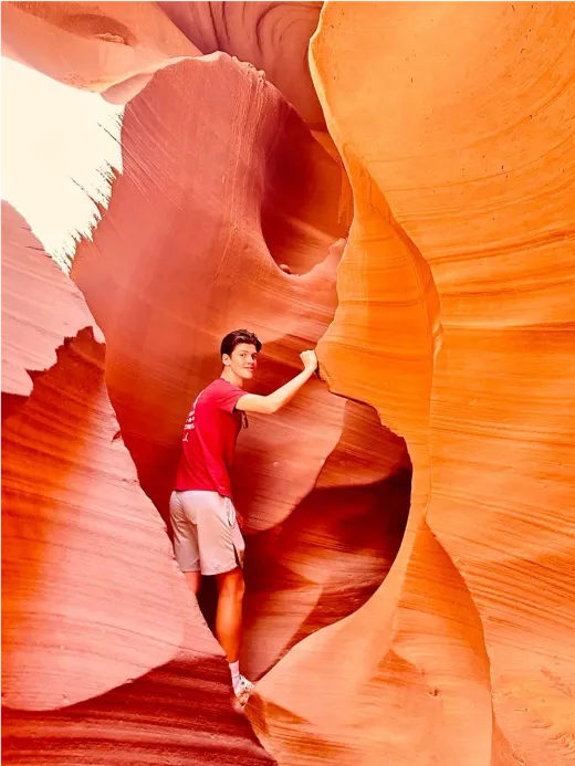 Tim in posa in uno stretto canyon di roccia arancione negli Stati Uniti.