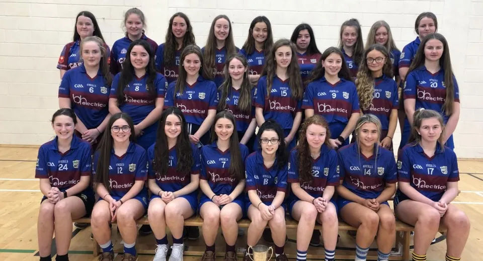 Un gruppo di studentesse della Ballingarry Presentation School posa in divisa sportiva all'interno di una palestra.