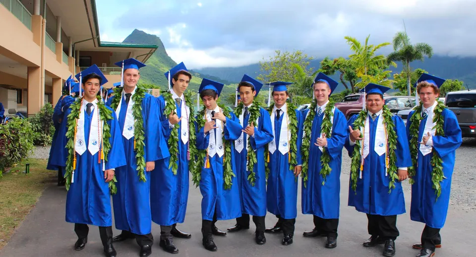 Un gruppo di diplomati della Le Jardin Academy si trova all'aperto davanti a un paesaggio tropicale.