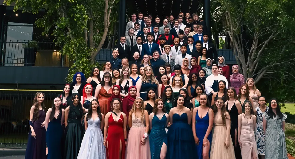 Un gruppo di studentesse e studenti della Salisbury High School si raccoglie all'aperto davanti a uno sfondo verde.