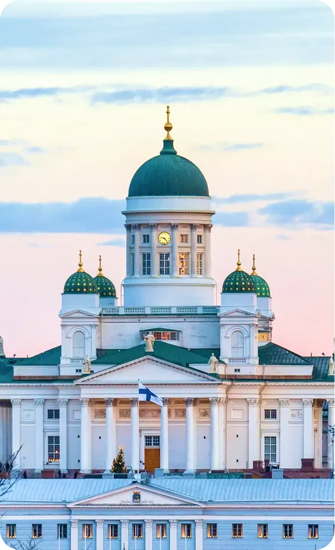 La cattedrale bianca di Helsinki con la cupola verde e la bandiera finlandese al tramonto
