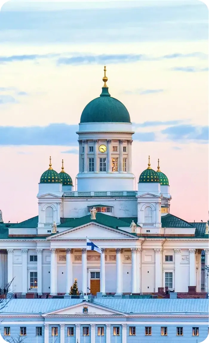 La cattedrale bianca di Helsinki con la cupola verde e la bandiera finlandese al tramonto