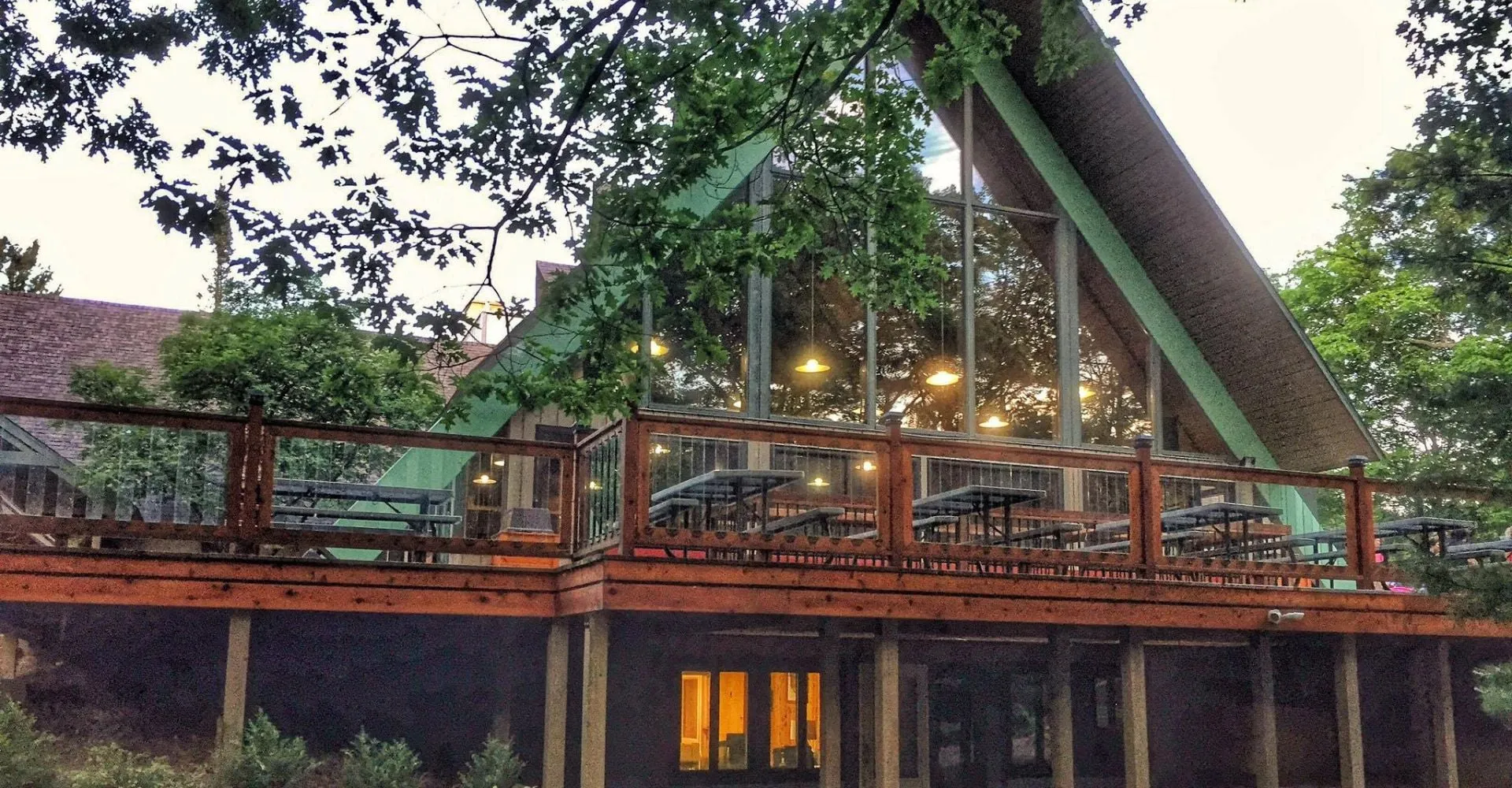 Un edificio della Leelanau School con un'ampia vetrata e una terrazza in legno con tavoli da picnic.