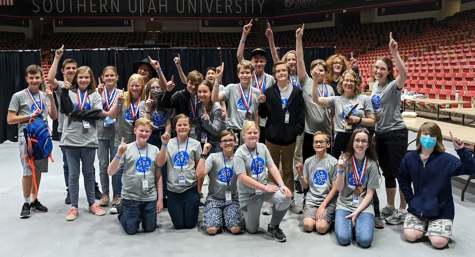 Un gruppo di studenti del Davis School District posa insieme in una grande sala con lo striscione della Southern Utah University sullo sfondo.