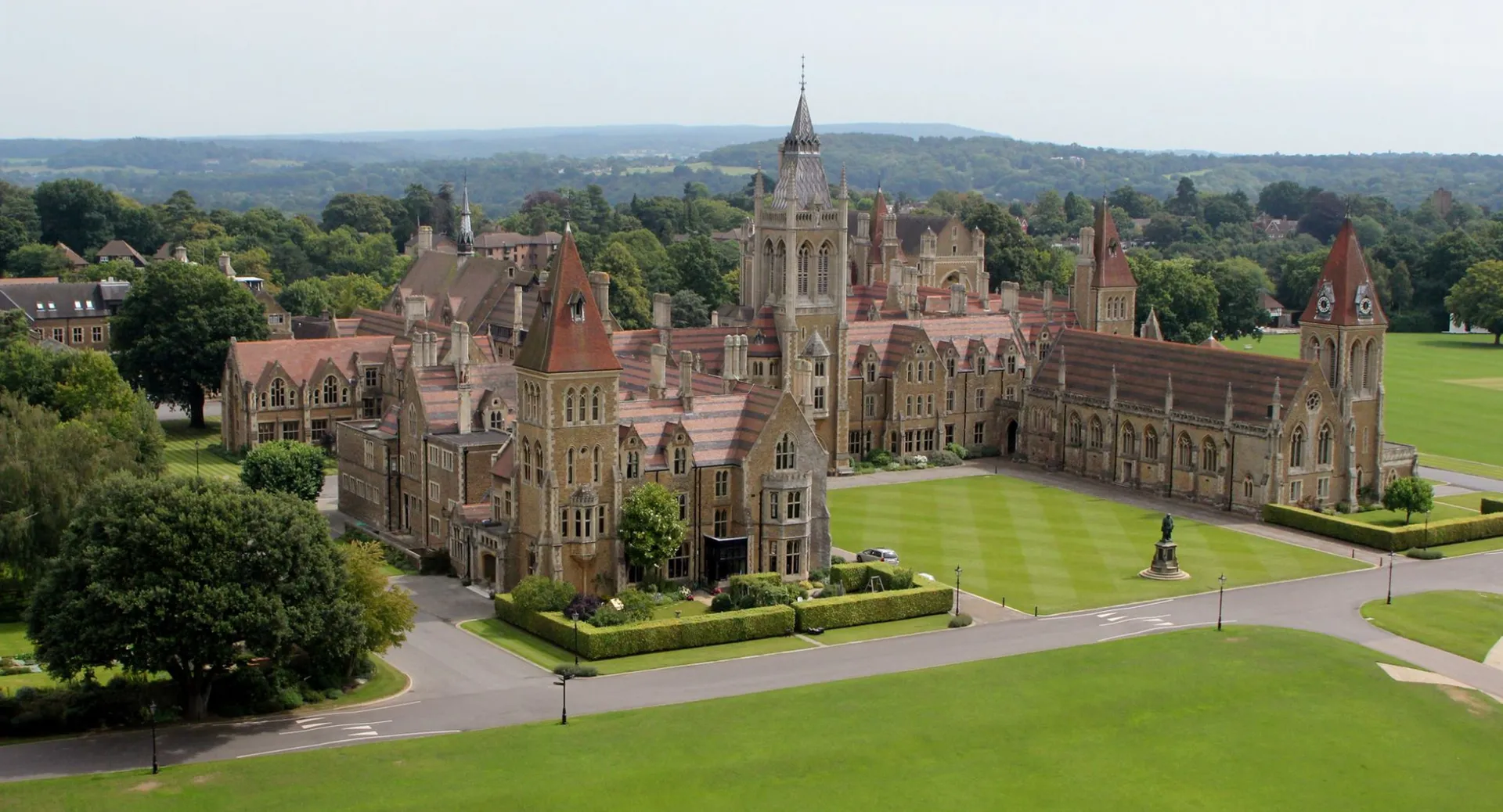 La Charterhouse School mostra un magnifico edificio simile a un castello con torri e prati verdi in un contesto rurale.