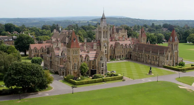 La Charterhouse School mostra un magnifico edificio simile a un castello con torri e prati verdi in un contesto rurale.
