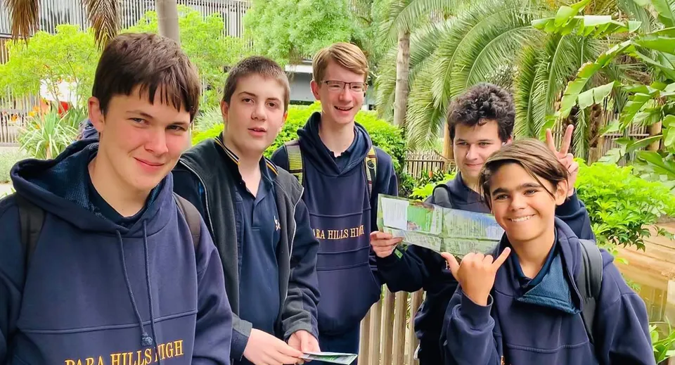 Un gruppo di studenti della Para Hills High School si trova insieme nel cortile della scuola dall'atmosfera tropicale.