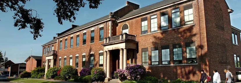 L'edificio in mattoni a più piani della Bellarmine Preparatory School è circondato da alberi e arbusti.