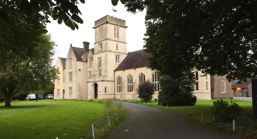 L'edificio storico con un'alta torre nel campus del Llandovery College è circondato da molto verde.