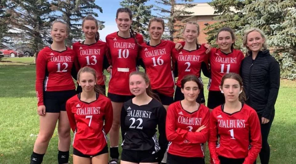 Un gruppo di giovani studentesse della Coalhurst High School posa insieme all'aperto su un prato con alberi sullo sfondo.