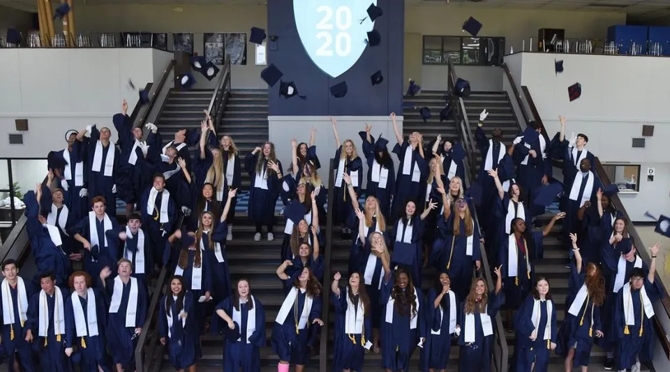 Un gruppo di studenti della Northpoint Christian School si raduna su una scalinata in abito da diploma per festeggiare il superamento del percorso scolastico.
