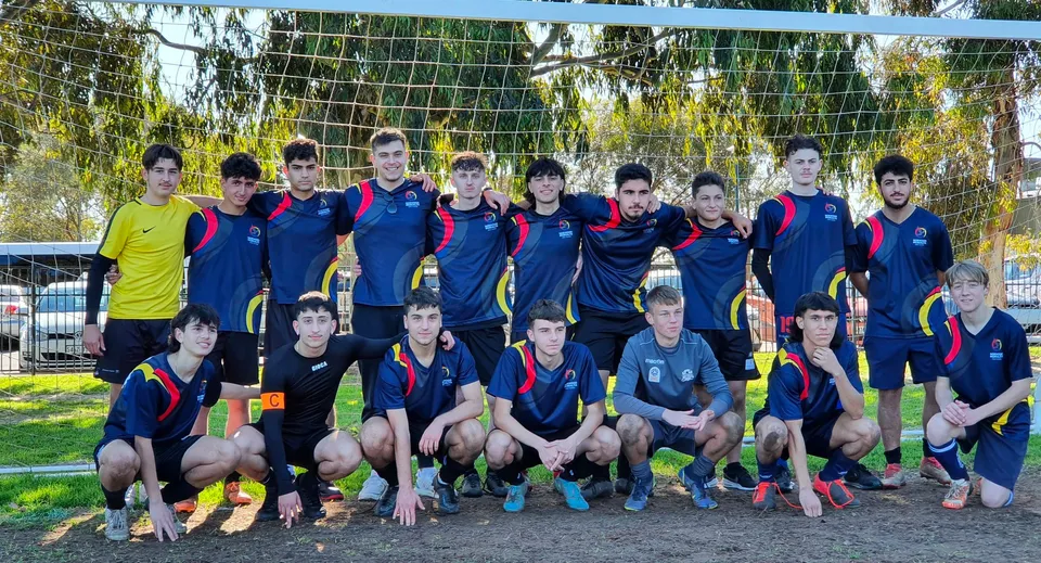 Un gruppo di studenti della Norwood International High School in posa davanti a una porta da calcio nel campus della scuola.