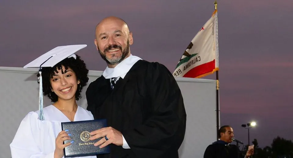 Un uomo e una donna in toga si trovano davanti a una bandiera durante una cerimonia di diploma al Duarte Unified School District.