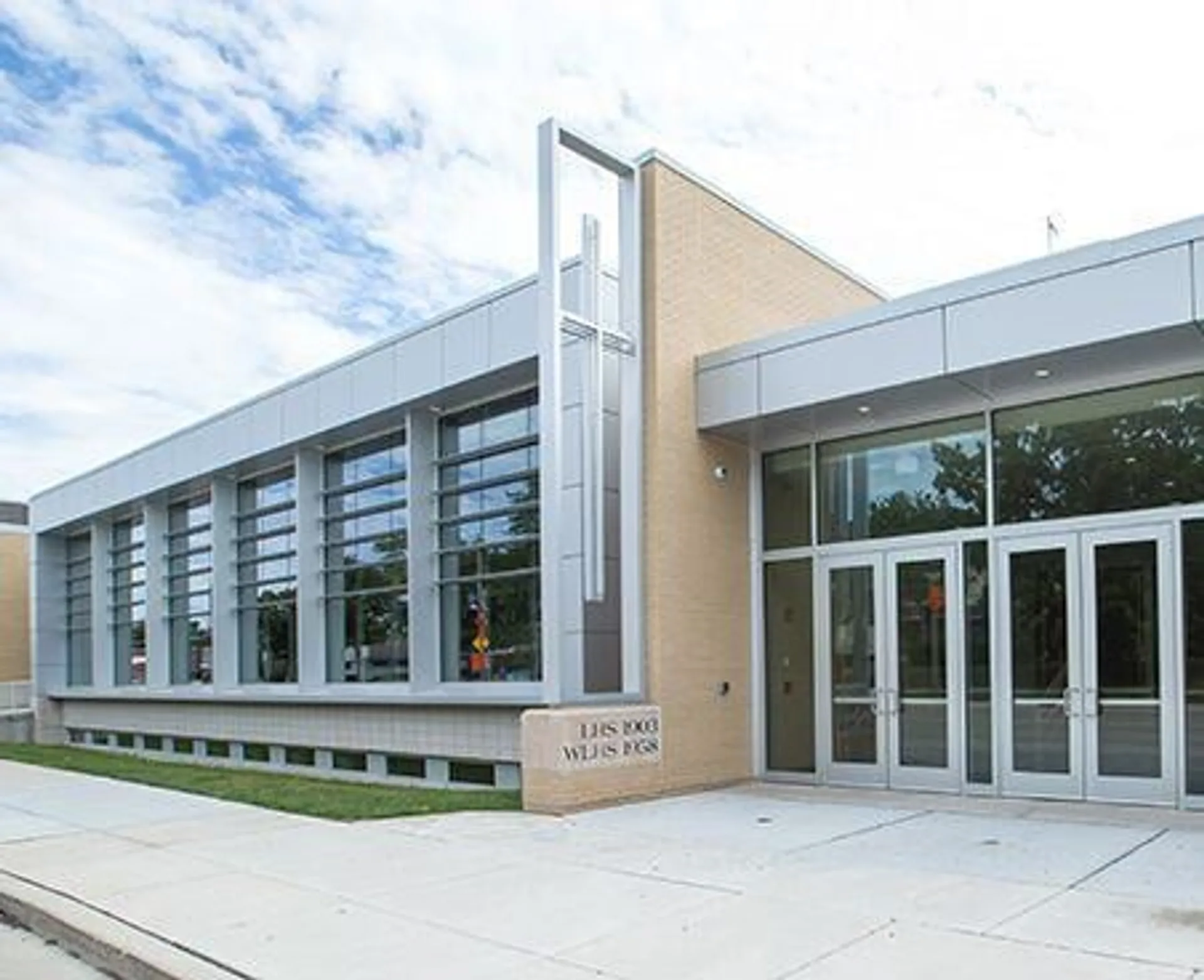 Il moderno edificio a più piani con grandi finestre in vetro della Wisconsin Lutheran High School è circondato da aree verdi sotto un cielo nuvoloso.