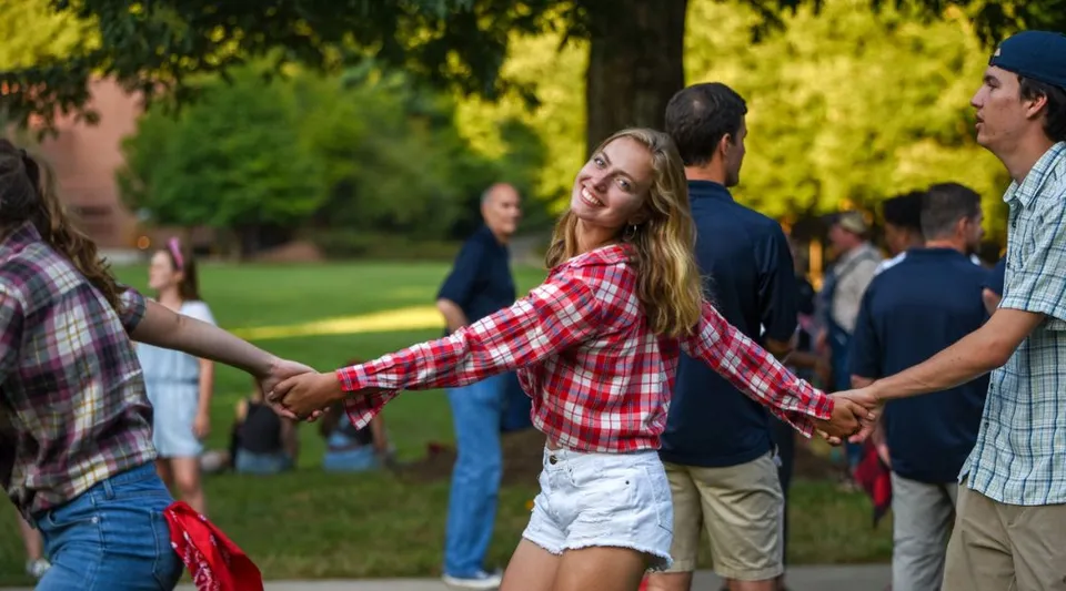 Studenti della Asheville School si ritrovano nel parco per un'attività di gruppo con alberi sullo sfondo.