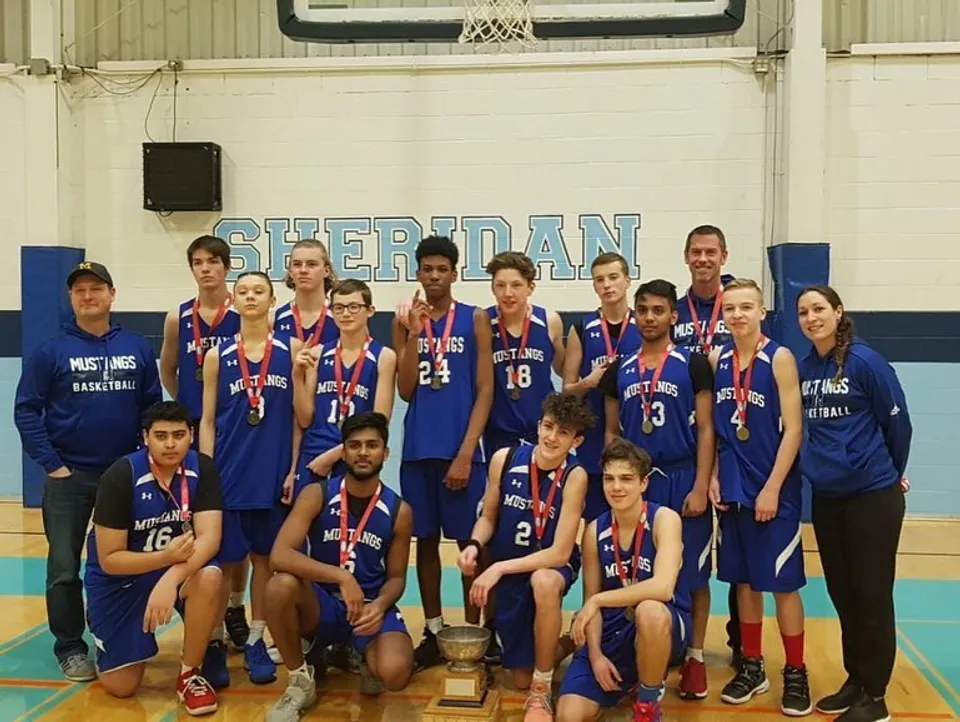 Un gruppo di studenti della Elsie MacGill Secondary School in posa nella palestra davanti a un cartello Sheridan.