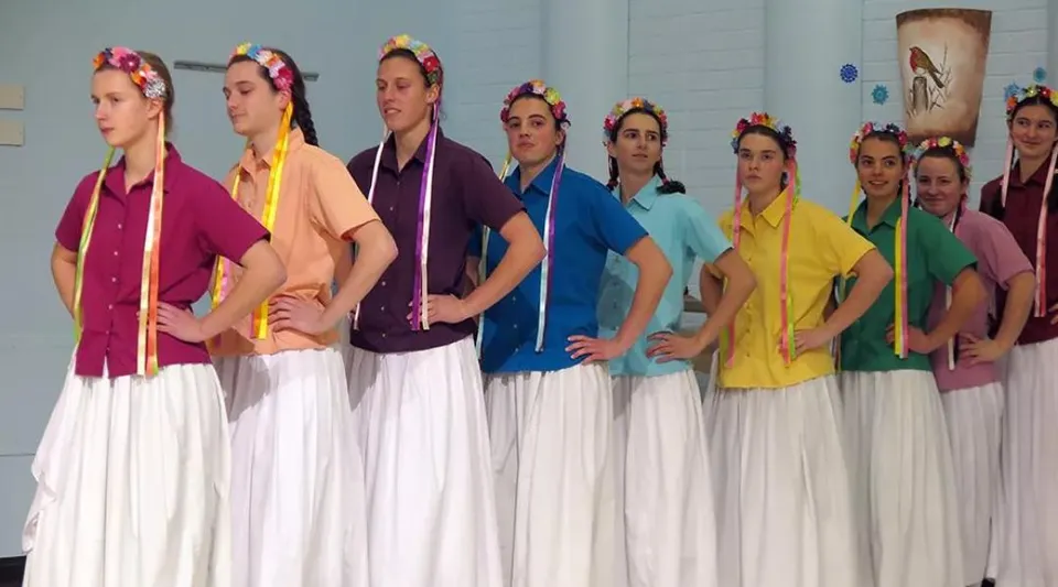Studentesse della Beech Grove School sul palco con abiti tradizionali colorati.