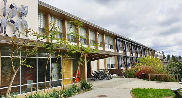 L'edificio della Sir Charles Tupper Secondary School con grandi vetrate, giovani alberi e biciclette parcheggiate.
