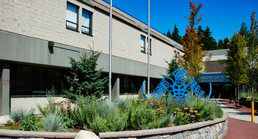 L'edificio moderno della Seycove Secondary School con una scultura blu e un giardino curato in primo piano.