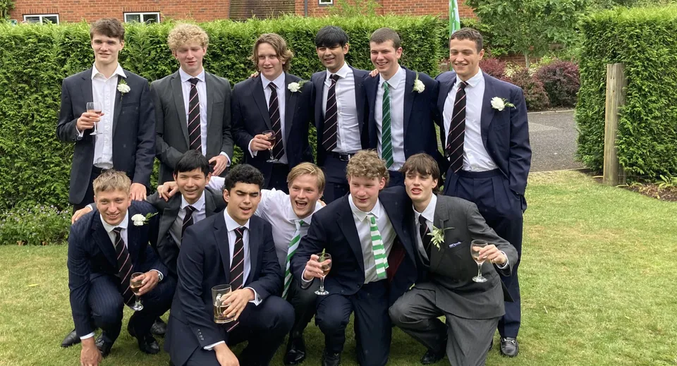 Un gruppo di studenti del Radley College posa davanti a un edificio in mattoni immerso nel verde.