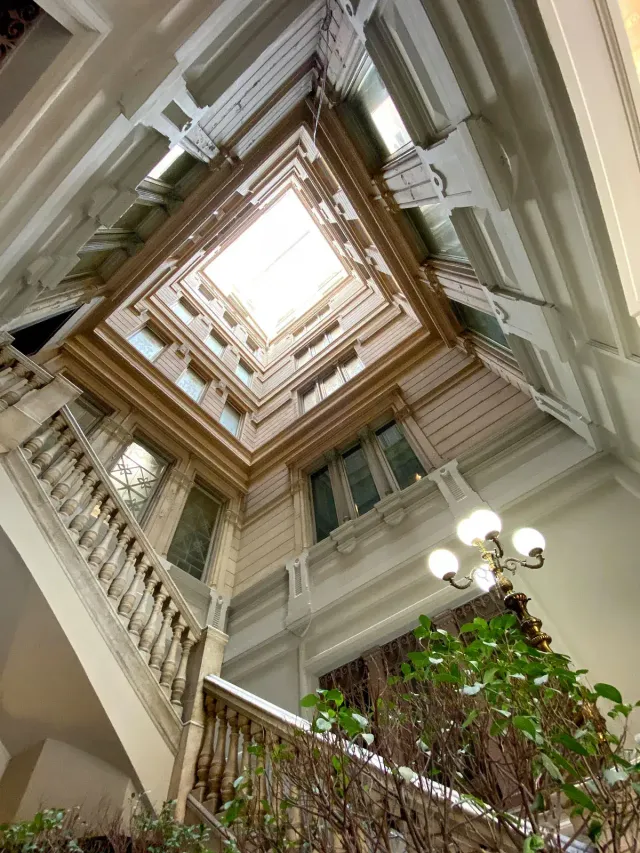 Patio interior de un edificio histórico visto desde abajo, con escalera de mármol y lucernario