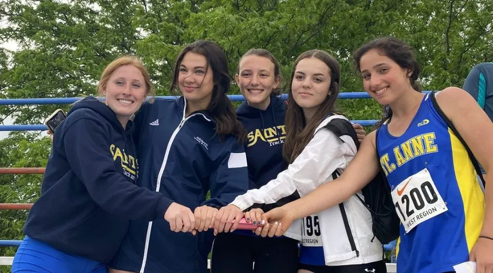 Cinque studentesse della St. Anne Catholic High School si trovano all'aperto in abbigliamento sportivo davanti a uno sfondo verde e sorridono alla fotocamera.