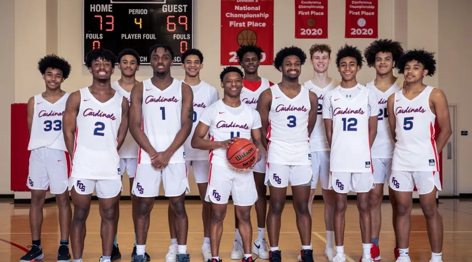 Un gruppo di giocatori di basket in divisa bianca con la scritta Colonials nella palestra della Fairfax Christian School.