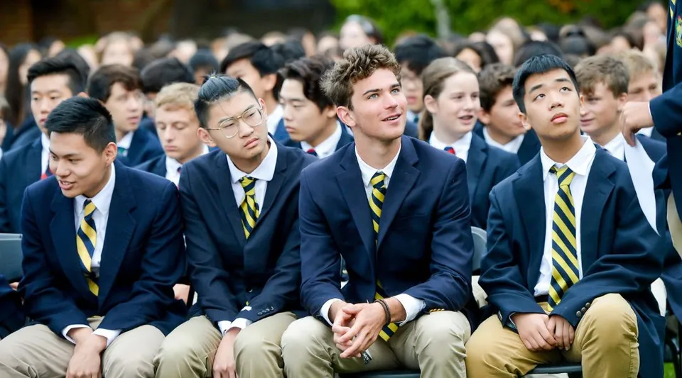 Un gruppo di studenti delle Annie Wright Schools in abiti formali è seduto insieme all'aperto.