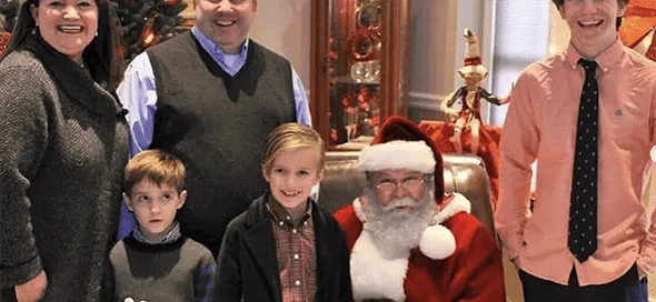 Familia sonriente posando en un salón junto a un hombre disfrazado de Santa Claus