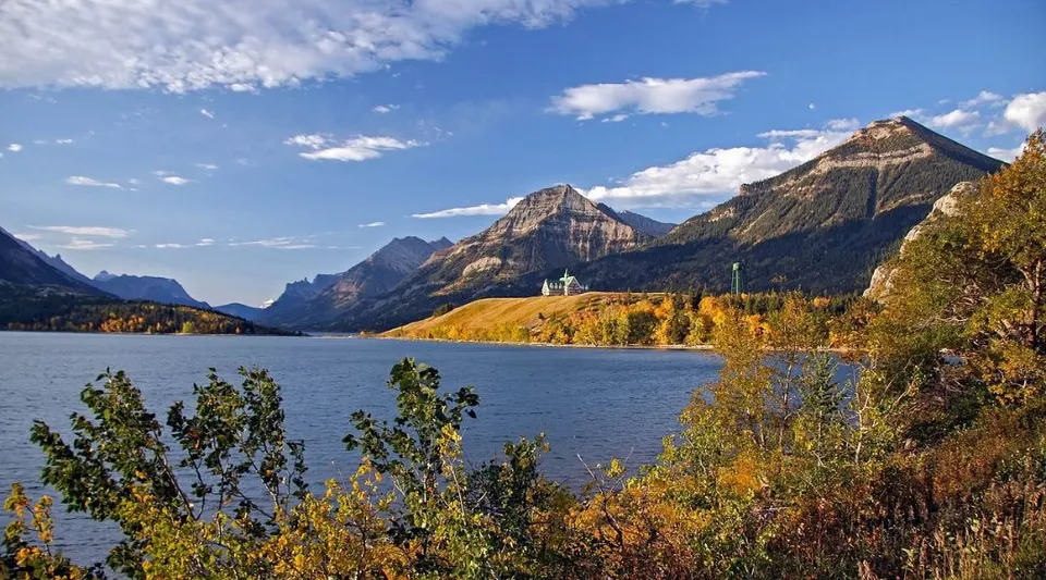 Un paesaggio montano canadese con un lago blu, alberi con colori autunnali e alte montagne.