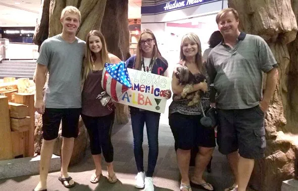 La familia anfitriona recibe a Alba en el aeropuerto con un cartel de bienvenida