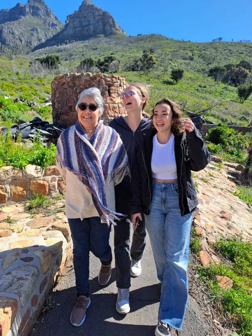 Tre persone sorridenti su un sentiero di montagna sotto una vetta rocciosa in Sudafrica
