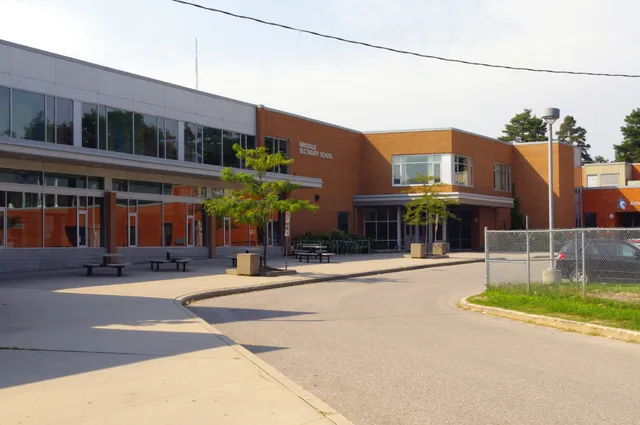 L'edificio moderno a più piani della Innisdale Secondary School con pareti in vetro ed elementi di facciata arancioni e grigi.