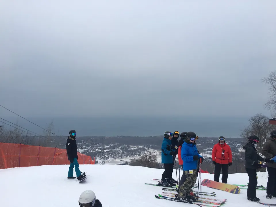 Un gruppo di studenti della Nelson High School si trova su un pendio innevato davanti a un paesaggio montano nebbioso.