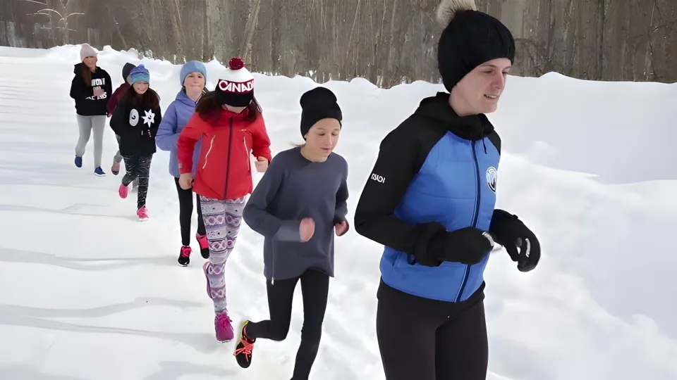 Studenti della École Sophie Morigeau camminano in un bosco innevato con alberi spogli indossando vestiti invernali caldi.