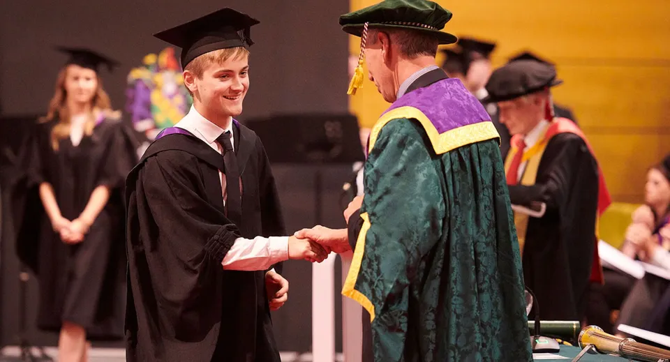 Due diplomati in toga si stringono la mano durante la cerimonia di diploma della Orangeville District Secondary School.