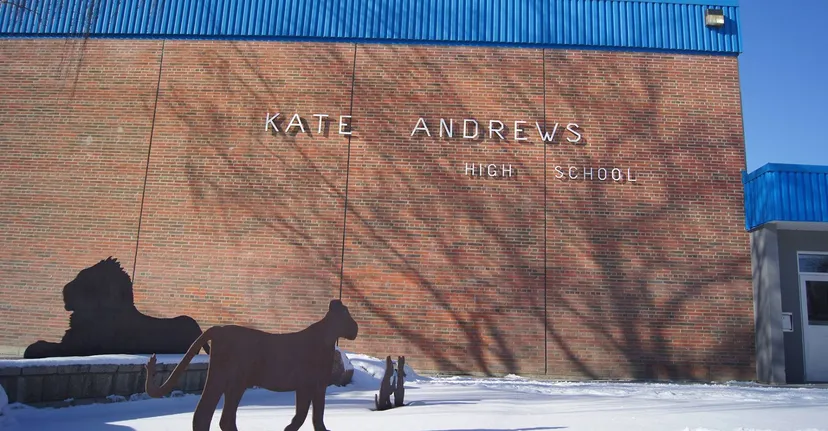 L'edificio in mattoni della Kate Andrews High School con la silhouette di un cavallo su uno sfondo innevato.