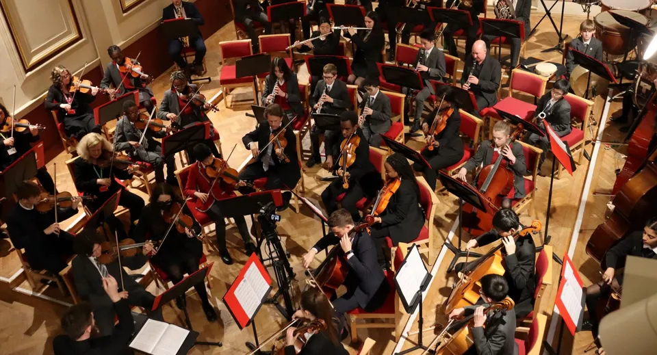 Un grande gruppo di diplomati della Uppingham School si riunisce in una splendida sala per la cerimonia di fine anno.